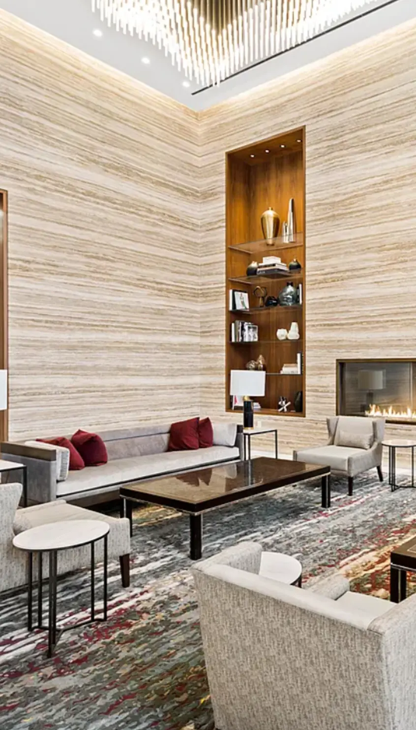 Elegant modern lobby at One West End Avenue, featuring high ceilings, designer lighting, built-in shelving, a sleek fireplace, and sophisticated seating — showcasing luxury New York residential amenities.